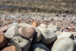 love heart shaped beach stone sat on pile of beach stones
